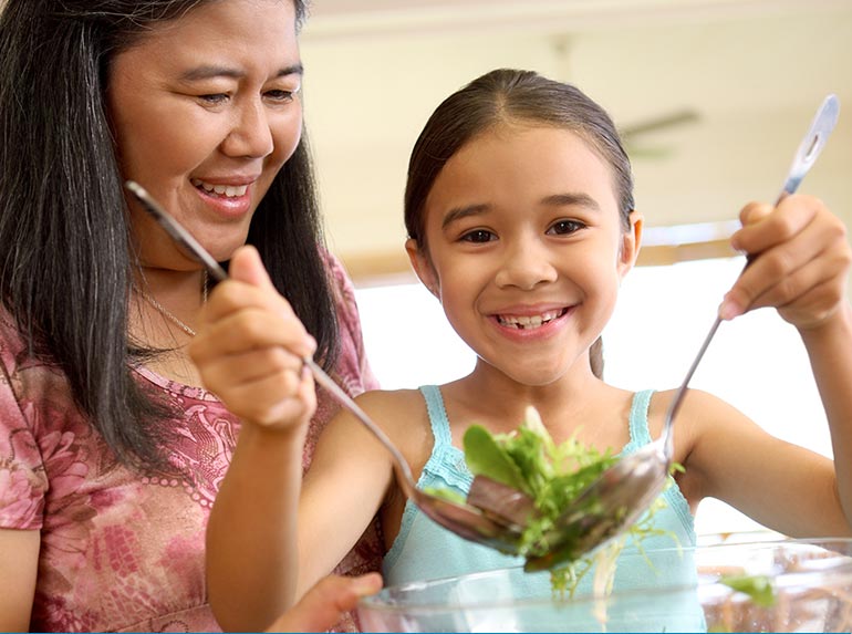 Girl making salad with Mom